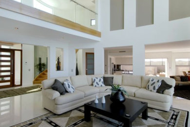 Стильный дизайн: большая парадная, открытая гостиная комната в стиле модернизм с белыми стенами, полом из керамической плитки и разноцветным полом - последний тренд