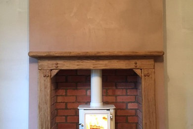 バークシャーにあるトラディショナルスタイルのおしゃれなリビング (薪ストーブ、木材の暖炉まわり) の写真