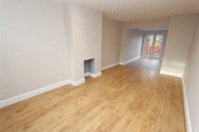 Medium sized contemporary living room in London with beige walls, light hardwood flooring and a standard fireplace.