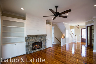 Example of a farmhouse open concept medium tone wood floor living room design in Other with a stone fireplace