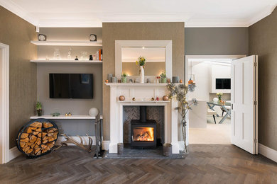 This is an example of a contemporary living room in London with beige walls, a wood burning stove, a stone fireplace surround and brown floors.
