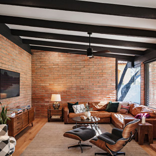 Example of a southwest medium tone wood floor and brown floor living room design in Phoenix with a standard fireplace and a wall-mounted tv