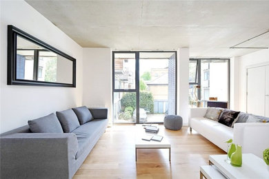 Cette photo montre un grand salon tendance ouvert avec un mur blanc et un sol en bois brun.