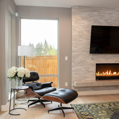 Example of a huge 1950s open concept light wood floor and beige floor living room design in Seattle with gray walls, a standard fireplace, a stone fireplace and a wall-mounted tv