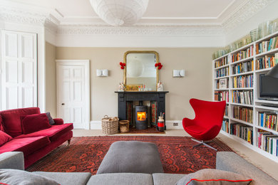 Exempel på ett klassiskt vardagsrum, med beige väggar, heltäckningsmatta, en öppen vedspis och en fristående TV