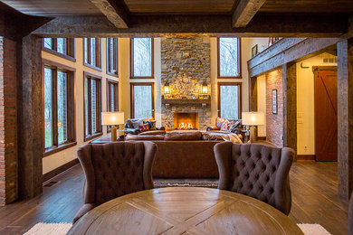 Example of a large mountain style open concept dark wood floor and brown floor living room design in Cincinnati with beige walls, a standard fireplace and a stone fireplace