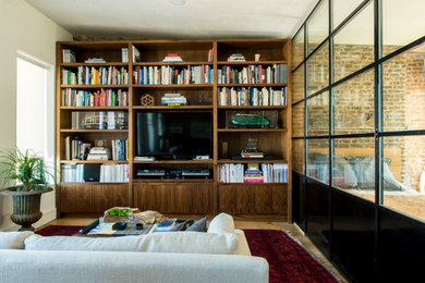Foto de biblioteca en casa abierta actual de tamaño medio con paredes blancas, suelo de madera en tonos medios y pared multimedia