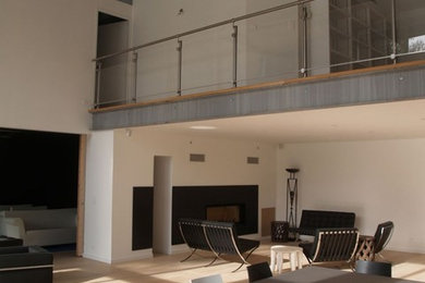 Imagen de salón abierto contemporáneo grande con paredes blancas, suelo de madera clara y chimenea lineal