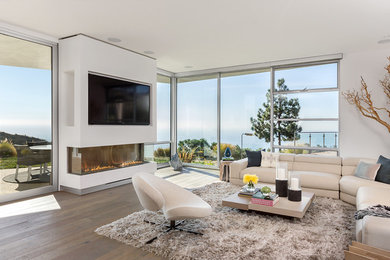 Großes, Offenes Modernes Wohnzimmer mit weißer Wandfarbe, hellem Holzboden, Kamin und verputzter Kaminumrandung in Los Angeles