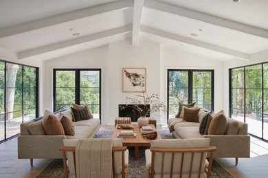 Design ideas for a traditional formal open plan living room in Los Angeles with white walls, medium hardwood flooring, a standard fireplace, no tv, brown floors and a vaulted ceiling.