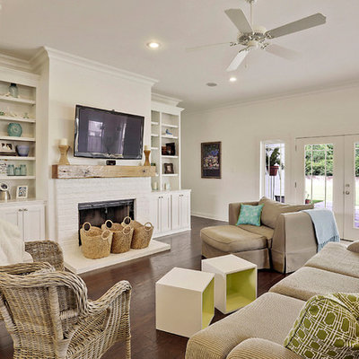 Example of a large beach style open concept dark wood floor living room design in New Orleans with white walls, a standard fireplace, a brick fireplace and a wall-mounted tv
