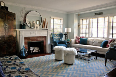 Cette photo montre un salon tendance de taille moyenne et ouvert avec un mur bleu, parquet foncé, une cheminée standard, un manteau de cheminée en brique et un téléviseur dissimulé.