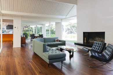 Example of a large 1960s open concept dark wood floor and brown floor living room design in San Francisco with white walls, a standard fireplace, a brick fireplace and no tv