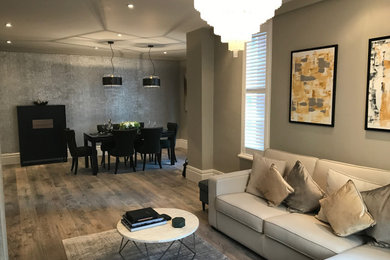 Ejemplo de salón para visitas abierto contemporáneo de tamaño medio con paredes beige, suelo laminado, suelo marrón, casetón y papel pintado