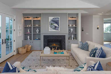 Inspiration for a large coastal open concept and formal medium tone wood floor and brown floor living room remodel in Los Angeles with gray walls, a standard fireplace, a tile fireplace and no tv