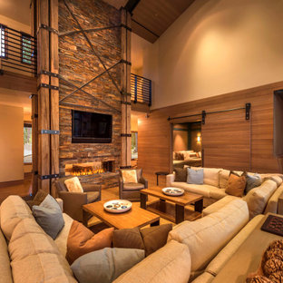 Imagen de salón abierto, abovedado y madera, rústico, extra grande, madera, con paredes beige, suelo de madera en tonos medios, chimenea lineal, marco de chimenea de piedra, televisor colgado en la pared, suelo marrón y madera