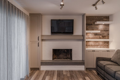 他の地域にある高級な中くらいなトランジショナルスタイルのおしゃれなLDK (白い壁、クッションフロア、標準型暖炉、レンガの暖炉まわり、壁掛け型テレビ、ベージュの床) の写真