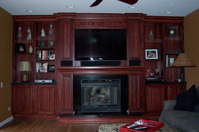 Living room - medium tone wood floor living room idea in Chicago with a standard fireplace, a wood fireplace surround and a media wall