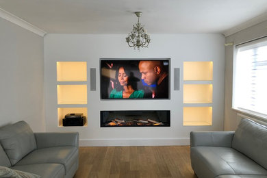 Medium sized modern living room in Sussex with white walls, a standard fireplace and a built-in media unit.
