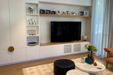 Idée de décoration pour un salon design de taille moyenne avec un mur blanc, parquet clair et un téléviseur fixé au mur.