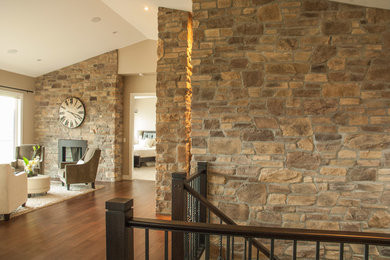 Example of a tuscan open concept dark wood floor living room design in Vancouver with beige walls, a standard fireplace, a stone fireplace and no tv
