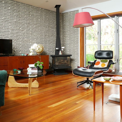 1960s medium tone wood floor living room photo in Melbourne with white walls, a wood stove and a tv stand