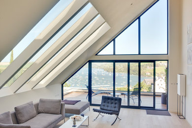 Large modern open plan living room in Devon with beige walls, light hardwood flooring and beige floors.