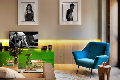 Ejemplo de salón actual de tamaño medio con suelo de madera clara, paredes beige, televisor independiente y alfombra