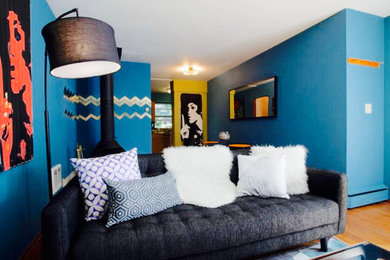ポートランドにある中くらいなミッドセンチュリースタイルのおしゃれな独立型リビング (青い壁、淡色無垢フローリング、コーナー設置型暖炉、据え置き型テレビ) の写真