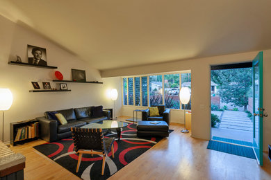 Small midcentury open plan living room in Santa Barbara with white walls and light hardwood flooring.