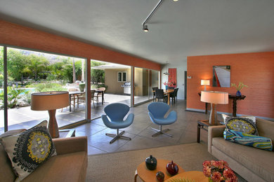 Mid-sized 1950s open concept concrete floor living room photo in Los Angeles with orange walls, a corner fireplace, a brick fireplace and a wall-mounted tv