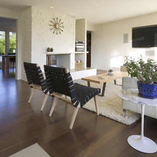 Modernes Wohnzimmer mit braunem Boden, weißer Wandfarbe, Kaminumrandung aus Backstein und Wand-TV in Seattle
