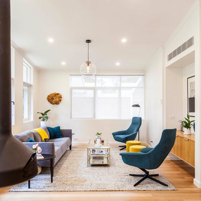 Mid-sized 1960s open concept medium tone wood floor and brown floor living room photo in Melbourne with white walls, a hanging fireplace and no tv