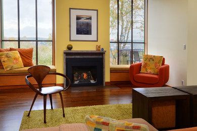 シアトルにある広いエクレクティックスタイルのおしゃれな独立型リビング (黄色い壁、無垢フローリング、標準型暖炉、タイルの暖炉まわり) の写真