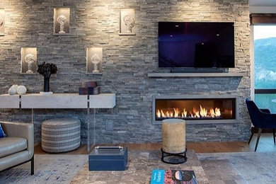 Modelo de salón abierto tradicional renovado con suelo de madera en tonos medios, chimenea lineal, marco de chimenea de piedra y televisor colgado en la pared