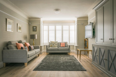 Imagen de salón para visitas cerrado clásico renovado de tamaño medio con paredes grises, suelo de madera clara y televisor colgado en la pared