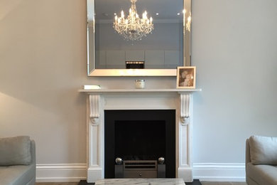 This is an example of a contemporary living room in Buckinghamshire with medium hardwood flooring, a standard fireplace, a stone fireplace surround and a wall mounted tv.