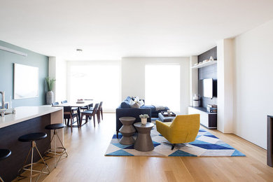 Immagine di un soggiorno minimalista con pareti bianche, pavimento in legno massello medio e TV a parete
