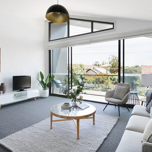 Photo of a contemporary formal living room in Melbourne with white walls, carpet, a freestanding tv and brown floor.