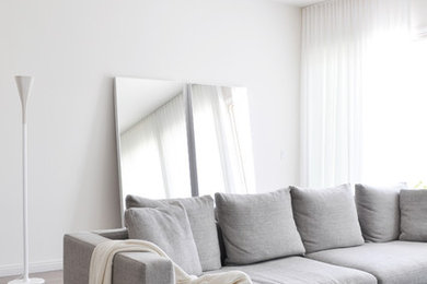 Стильный дизайн: парадная, изолированная гостиная комната среднего размера в современном стиле с белыми стенами, светлым паркетным полом и телевизором на стене - последний тренд
