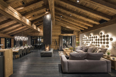 Foto de salón abierto contemporáneo extra grande con suelo de madera oscura, chimenea de doble cara y marco de chimenea de hormigón