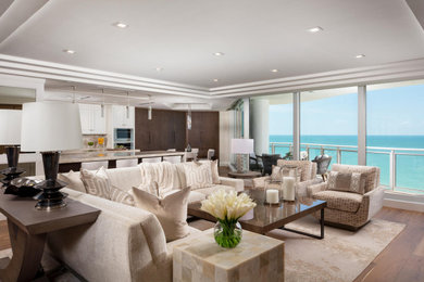 Example of a large beach style open concept medium tone wood floor and brown floor living room design in Miami with white walls, a standard fireplace, a stone fireplace and a media wall