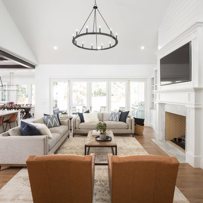 Example of a cottage open concept medium tone wood floor and brown floor living room design in Salt Lake City with white walls, a standard fireplace, a stone fireplace and a wall-mounted tv