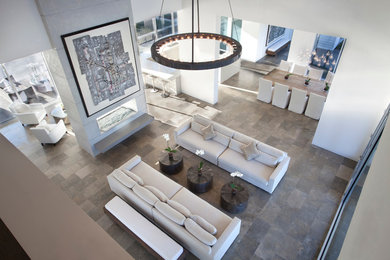 Expansive contemporary open plan living room in New Orleans with white walls, limestone flooring, a two-sided fireplace and a plastered fireplace surround.