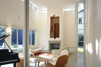 На фото: большая парадная, открытая гостиная комната в стиле модернизм с белыми стенами, полом из известняка, стандартным камином и фасадом камина из камня без телевизора с