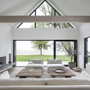 Modelo de salón abierto, minimalista, con paredes blancas, suelo de madera clara, chimenea tradicional y marco de chimenea de yeso