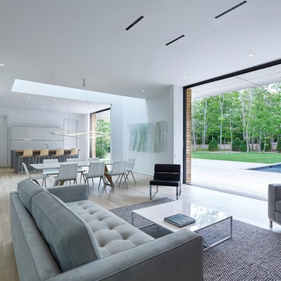Example of a minimalist open concept light wood floor and beige floor living room design in New York with white walls