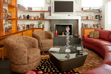 Imagen de biblioteca en casa abierta actual grande con paredes blancas, todas las chimeneas, marco de chimenea de piedra y televisor colgado en la pared