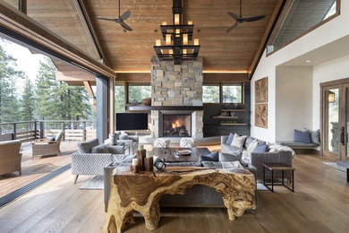 Photo of a rustic living room in San Francisco with white walls, dark hardwood flooring, a standard fireplace, a stone fireplace surround, a freestanding tv and brown floors.