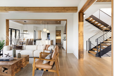 Inspiration for a country open concept light wood floor, brown floor and exposed beam living room remodel in Minneapolis with white walls, a standard fireplace, a stone fireplace and a wall-mounted tv